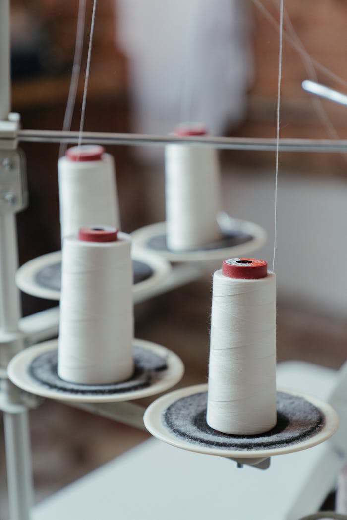 Detailed image of white sewing threads on spools in a workshop setting.