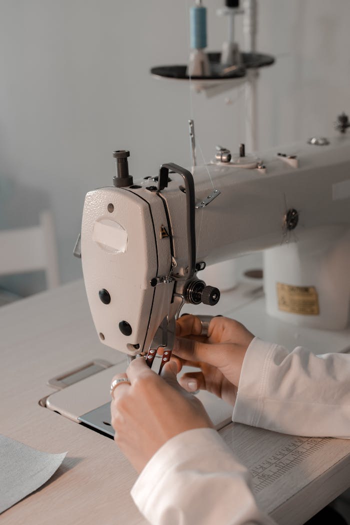 Close-up of a dressmaker using a sewing machine in a workshop, focusing on hands and details.